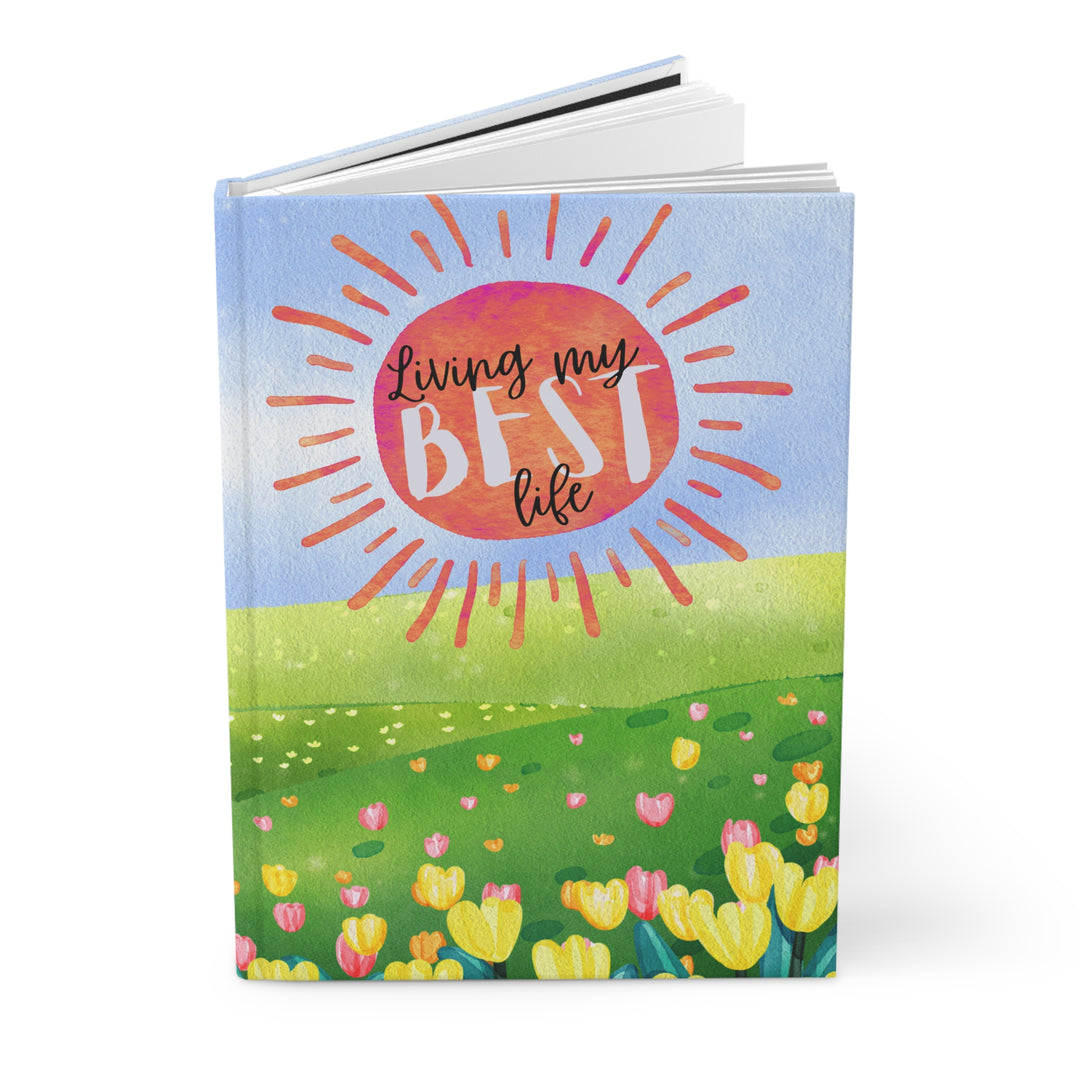 "Living my best life" in painted style orange sun like burst over blue sky with a meadow and tulips - open