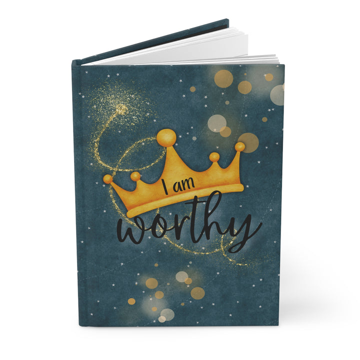 journal open with dark blue gray cover, silver and gold circles and a gold crown. Says "I am worthy"