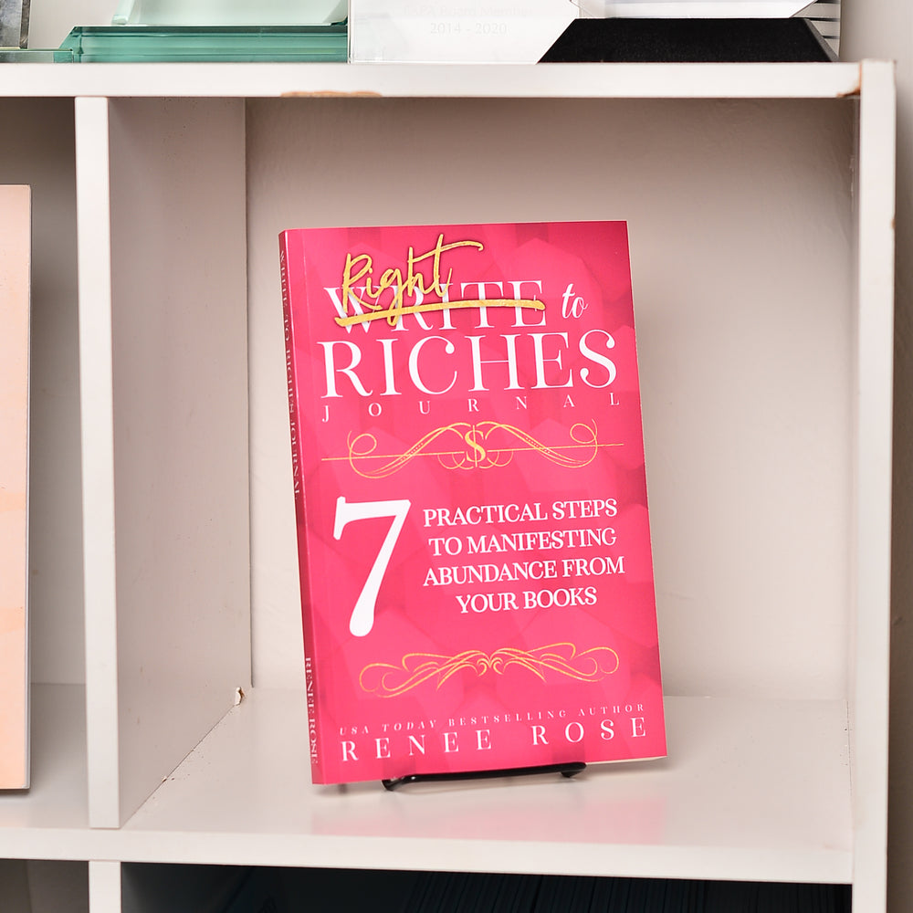 Pink book titled 'Write to Riches Journal' on a shelf